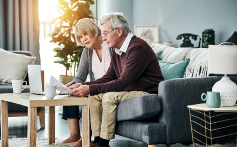 Retired couple sitting on a couch reviewing documents together
